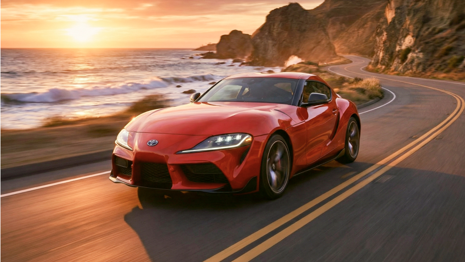 Red Toyota GR Supra cruising along Pacific Coast Highway (PCH).